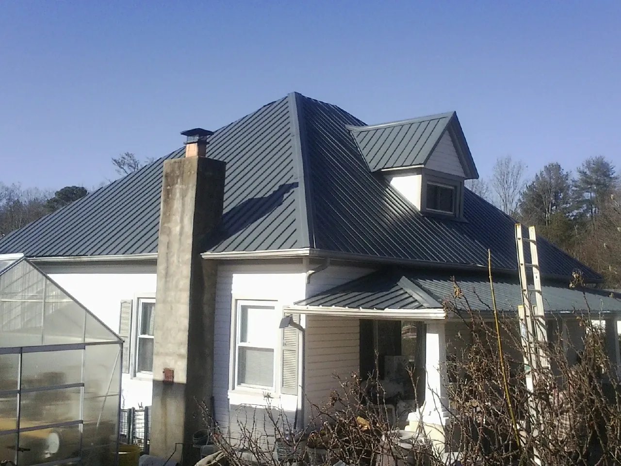 Dark blue standing seam metal roof on a white farmhouse with dormer — Slate & Tile Roof Repair by Roofing Brothers in Mineral