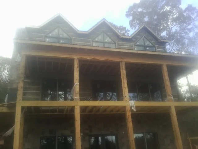 Dormers and porch framing on a large log home under construction — Roof Coating work by our crew in Mineral