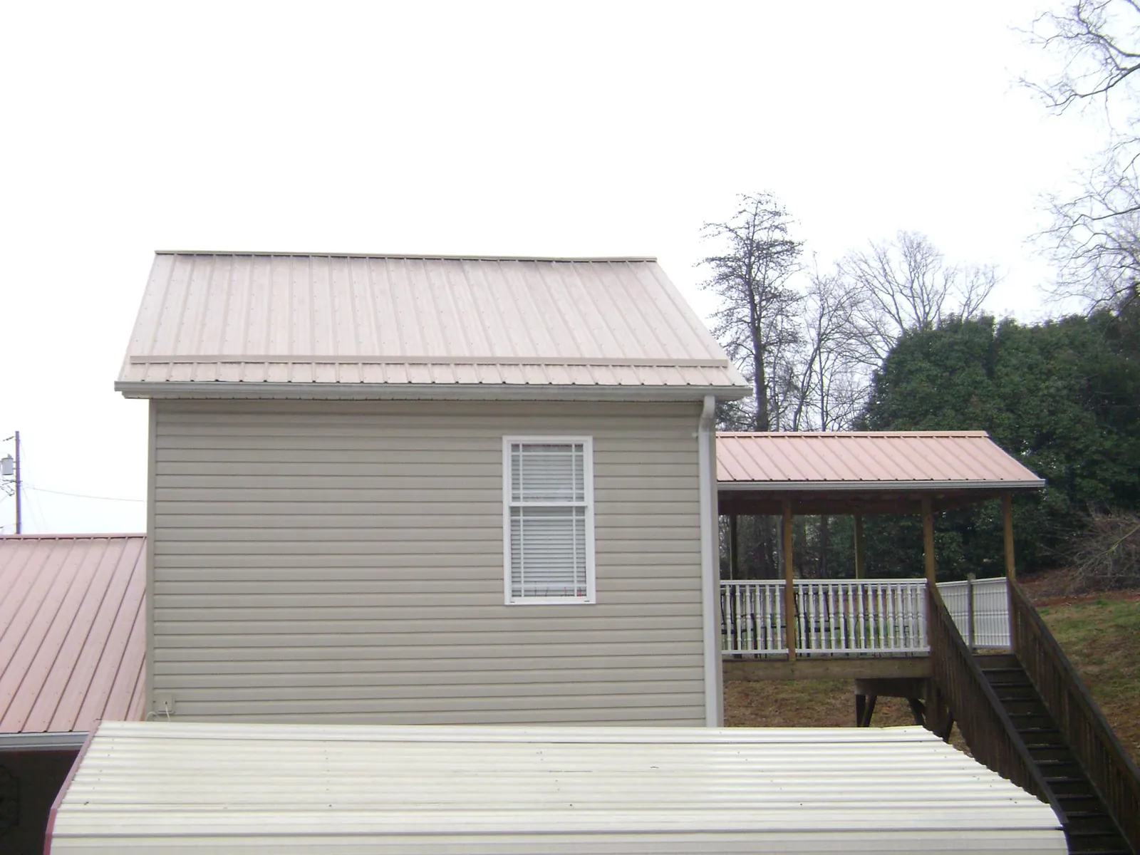 Tan metal roofs on a two story addition and attached porch, from a Roof Replacement job in Mineral